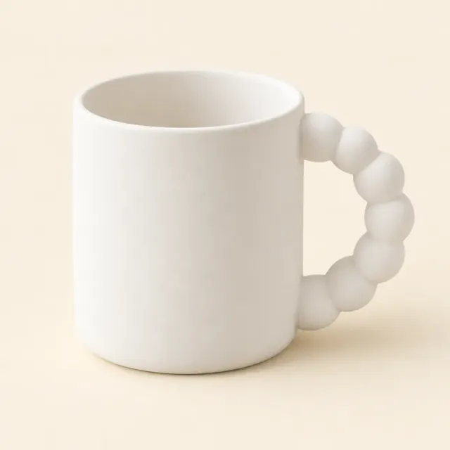 Unpainted white ceramic mug with a straight body and a handle made of beads