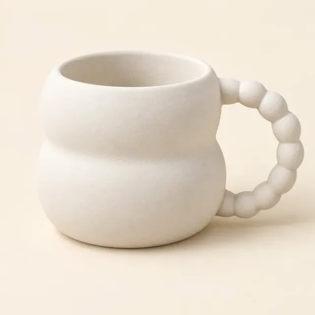 Unpainted white ceramic mug with a rounded, bubble-shaped body and a beaded handle