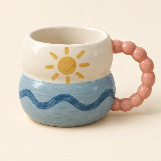 Bubble mug painted with a yellow sun, blue waves and a pink bead handle.