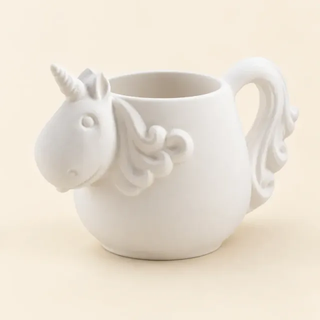 Unpainted white ceramic mug shaped like a unicorn, with a horn, a curly mane and a tail for a handle