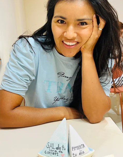 Paola at the workshop table beside a hand-painted salt and pepper sailboat